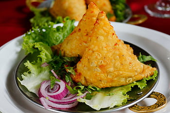 Close-up of crispy samosas served with fresh lettuce and onion rings. HD wallpaper