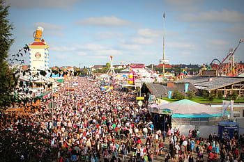 A lively scene at Oktoberfest in Munich with a massive crowd enjoying the festivities and attractions. HD wallpaper