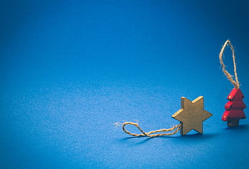 A wooden star and Christmas tree ornament on a vibrant blue background, symbolizing the holiday season. HD wallpaper