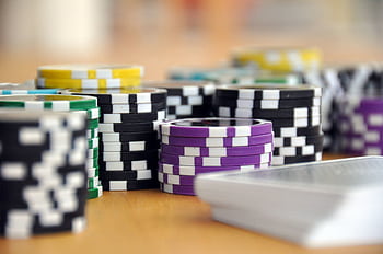 A close-up shot of stacked poker chips and playing cards on a table, perfect for casino and gambling themes. HD wallpaper