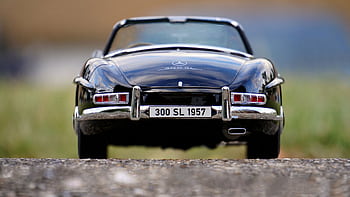 Rear view of a vintage 1957 Mercedes 300 SL convertible, highlighting its emblem and classic design. HD wallpaper