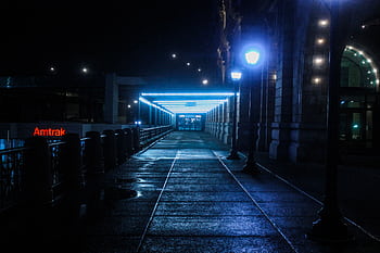 A moody, illuminated pathway at a train station during night with glowing lamps. HD wallpaper