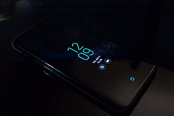 Close-up of a smart in the dark displaying digital clock and notifications. HD wallpaper