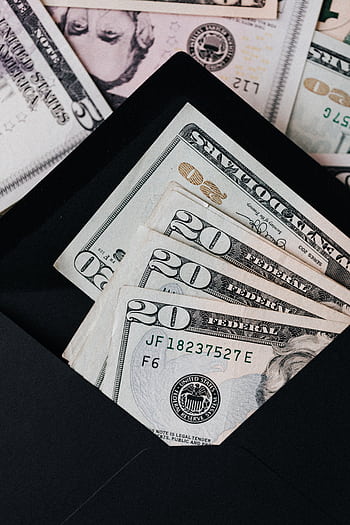 Close-up of US dollar bills in a black envelope, symbolizing savings or budgeting. HD phone wallpaper
