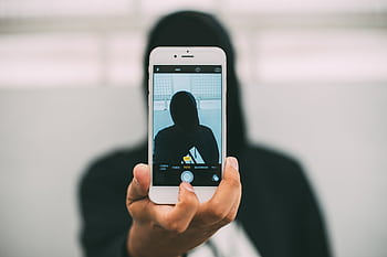 A person in a hoodie takes a mysterious selfie with a smart. HD wallpaper