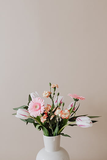 A delicate arrangement of pink flowers in a ceramic vase on a beige background. HD phone wallpaper