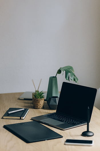 A minimalist home office setup featuring a laptop, notebook, and plant for a productive workspace. HD phone wallpaper