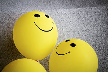 Three yellow smiley face balloons creating a cheerful and bright atmosphere indoors. HD wallpaper