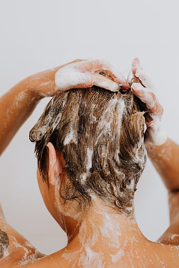 Close-up of a woman washing hair with foam shampoo, focused on hygiene and care. HD phone wallpaper