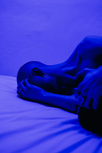 A tattooed man lying in blue light, symbolizing isolation and stress. HD phone wallpaper