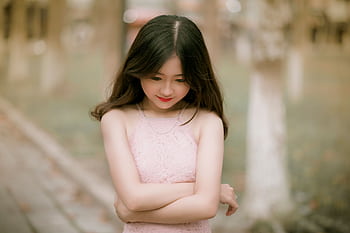 Portrait of a young woman with long hair in a pink lace dress, outdoors in a serene setting. HD wallpaper
