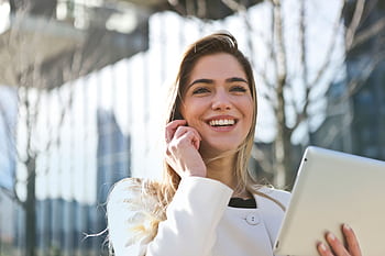 Confident businesswoman using her tablet and , smiling outdoors in sunlight. HD wallpaper