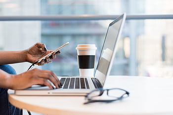 Close-up of hands using a laptop and with coffee on a modern office desk. HD wallpaper