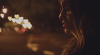 A captivating side profile of a woman at night with heart-shaped bokeh lights creating a dreamy mood. HD wallpaper
