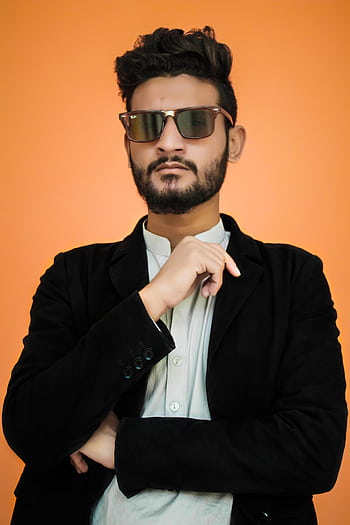 Confident man in sunglasses posing against a vibrant orange backdrop. HD phone wallpaper