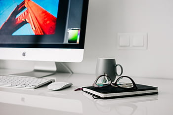 Stylish office workspace featuring a computer, glasses, and notebook. HD wallpaper
