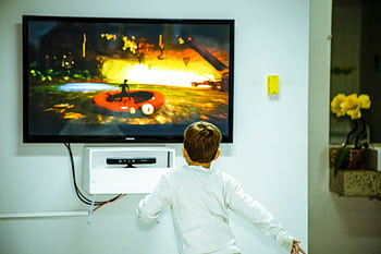 A young boy intensely watching and interacting with a video game on a television screen indoors. HD wallpaper