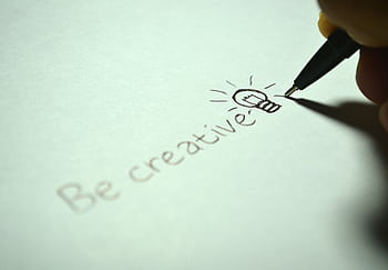 Close-up of handwritten 'Be creative' with a light bulb sketch on paper. HD wallpaper
