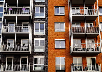 Detailed view of a modern apartment building's exterior with balconies and glass windows. HD wallpaper
