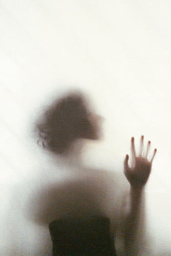A dreamy silhouette of a woman touching a translucent surface, evoking mystery. HD phone wallpaper