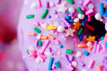 Vibrant close-up of a pink donut topped with multicolored sprinkles, perfect for party themes. HD wallpaper