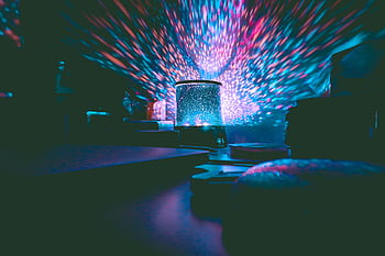 A colorful galaxy projector casting vibrant lights in a dark room. Perfect for setting a calm ambiance. HD wallpaper