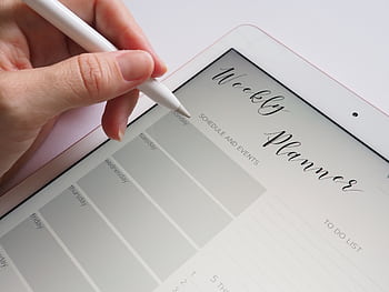 A stylus writing in a digital weekly planner on a tablet screen, ideal for organization. HD wallpaper