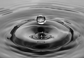Dramatic black and white of a water droplet creating ripples, showcasing macro graphy artistry. HD wallpaper