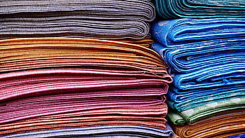 Vibrant and neatly stacked fabrics showcasing an array of colors and patterns, ideal for fashion and textile design. HD wallpaper