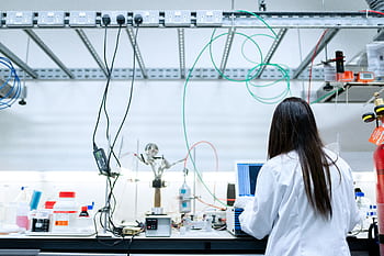 A female scientist conducting research in a contemporary laboratory full of equipment. HD wallpaper