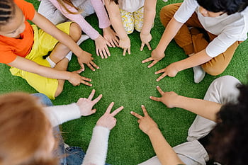Children sitting in a circle playing fun team games on artificial grass. HD wallpaper
