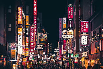 Night view of a busy Tokyo street with vibrant neon signs and people walking in Shinjuku, Japan. HD wallpaper