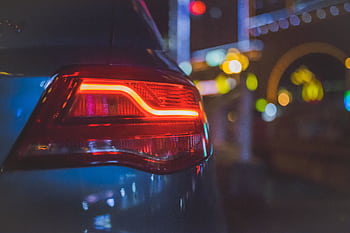 Close-up of a car's tail light with colorful bokeh background in an urban night setting. HD wallpaper
