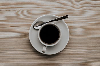 A coffee cup with a saucer and spoon on a textured wooden surface, viewed from above. HD wallpaper