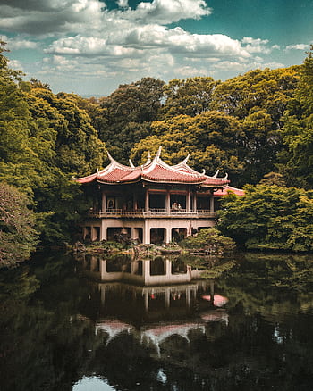 A beautiful traditional Japanese pagoda surrounded by lush greenery and reflected in a peaceful lake. HD phone wallpaper