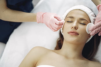 Woman enjoying a soothing facial treatment in a serene spa setting, promoting relaxation and beauty. HD wallpaper