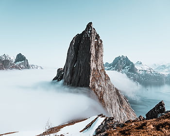 Epic winter landscape of sharp mountain peaks surrounded by mist in Troms, Norway. HD wallpaper