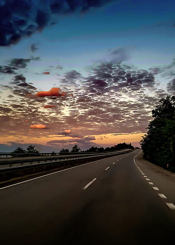 Serene highway scene with a stunning sunset sky, perfect for travel themes. HD phone wallpaper