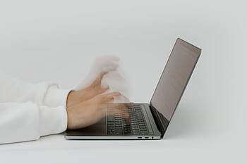 Hands rapidly typing on a laptop, illustrating speed and technology in a digital work environment. HD wallpaper
