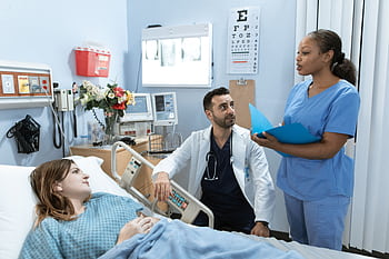 Doctors and nurse discussing patient's treatment in a hospital room. HD wallpaper