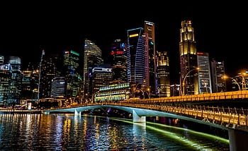 Stunning Singapore cityscape featuring vibrant skyscrapers, illuminated bridge, and reflections over the river at night. HD wallpaper