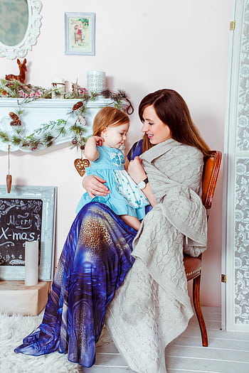 A mother lovingly holding her daughter, surrounded by cozy holiday decorations. HD phone wallpaper