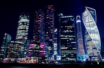 Illuminated night view of Moscow's modern skyscrapers, showcasing vibrant city lights and urban architecture. HD wallpaper