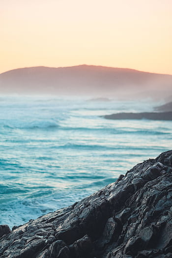 A stunning view of waves crashing against rocks at sunset along the South African coast. HD phone wallpaper