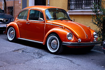 A classic orange Volkswagen Beetle parked on a street in Istanbul. HD wallpaper
