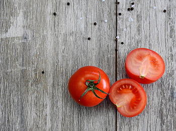 Close-up of ripe tomatoes on a rustic wooden table with peppercorns. HD wallpaper