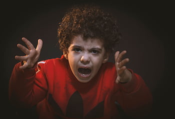 A young child expressing strong emotions during a studio portrait shoot. HD wallpaper