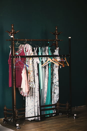 A stylish collection of dresses on a wooden clothes rack against a dark wall, creating a chic aesthetic. HD phone wallpaper