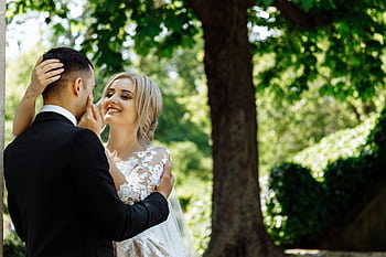Bride and groom sharing a tender moment under a tree in a Parisian garden. HD wallpaper