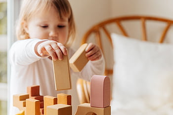 Young child playing with wooden blocks indoors, engaging in creative play and childhood learning. HD wallpaper